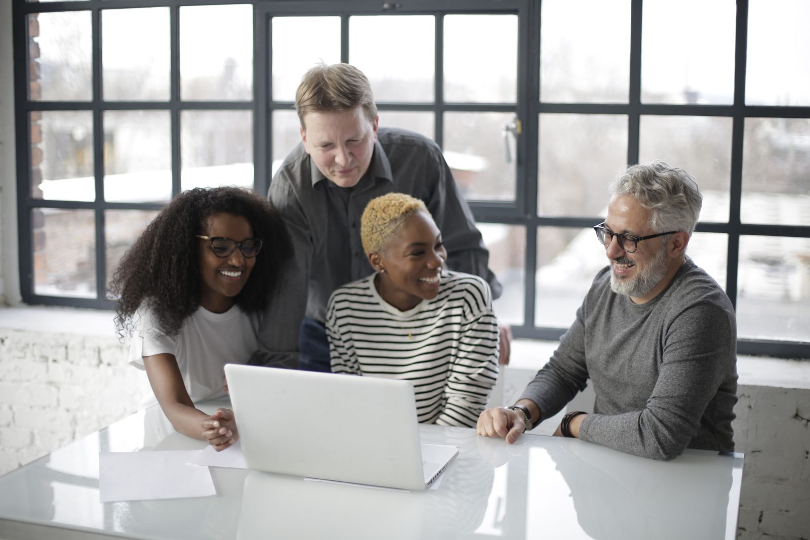 Professionals collaborating around a laptop in a bright office